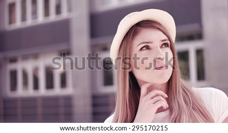 Close up Thoughtful Pretty Blond Young Woman Wearing White Hat, Looking Up Seriously Against the School Building.