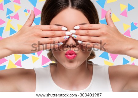 pretty woman with colorful gel nails hiding her eyes with fingers