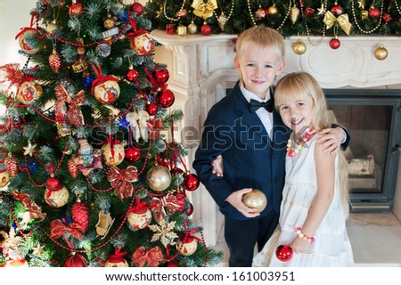 Happy brother and sister are embracing  near Christmas tree. little friends enjoying New Year party, Christmastime holidays, best friends, happiness concept
