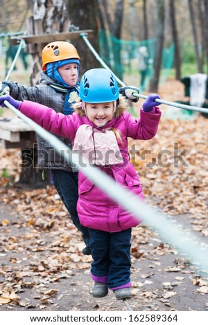 Cute brother and sister enjoying a autumn day in a climbing adventure activity park