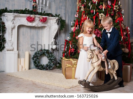 Happy brother and sister are playing near Christmas tree. little friends enjoying New Year party, Christmastime holidays, best friends, happiness concept