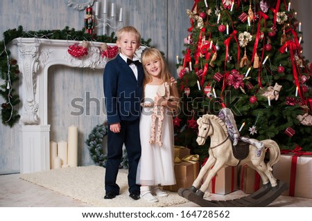 Happy brother and sister are embracing near Christmas tree. little friends enjoying New Year party, Christmastime holidays, best friends, happiness concept