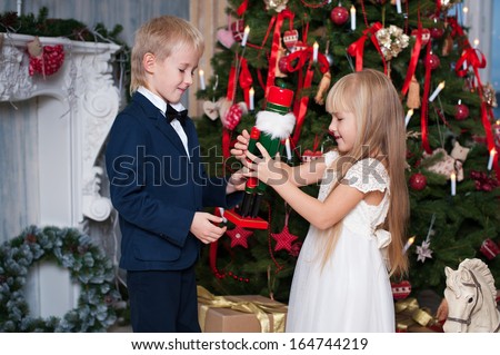 Happy brother and sister are playing near Christmas tree. little friends enjoying New Year party, Christmastime holidays, best friends, happiness concept