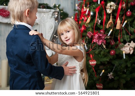 Happy brother and sister dancing near Christmas tree. little friends enjoying New Year party, Christmastime holidays, best friends, happiness concept