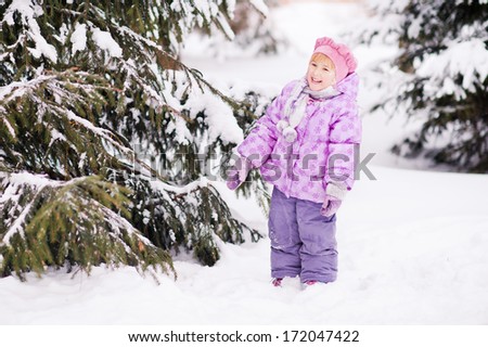cute laughing girl face in the snow, which fell from a tree in the forest