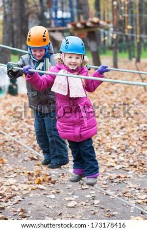 Cute brother and sister enjoying an autumn day in a climbing adventure activity park