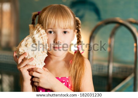 close up portrait of little girl with sea shell in her hands in the swimming pool in sport club