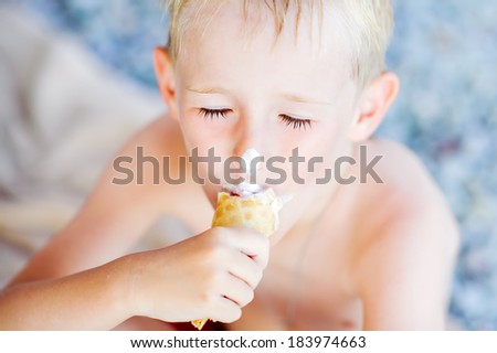 little boy with eyes closed eating ice cream in the summer