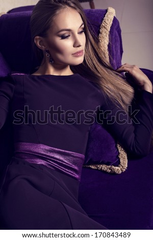 beautiful girl with long hair in purple dress lying on divan