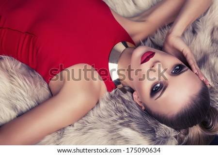 Sexy Girl In Red Dress Lying On Fur Coat