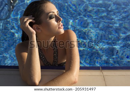 fashion photo of sexy beautiful girl with long wet hair in black  bikini relaxing in swimming pool