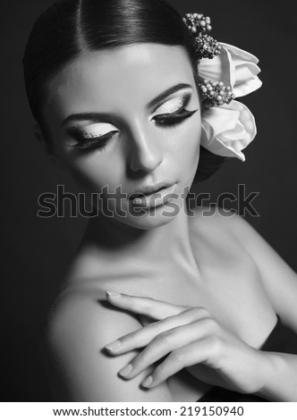 black and white fashion studio portrait of beautiful model with dark hair with bright makeup and hair accessory