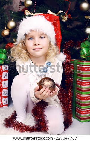 cute beautiful little girls in winter clothes posing beside a  christmas tree and presents