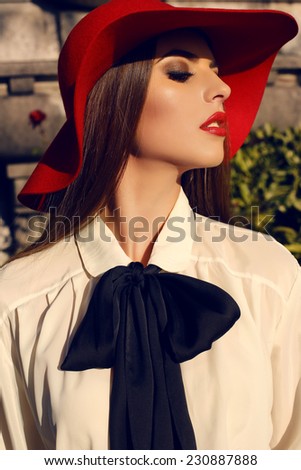 fashion outdoor photo of beautiful ladylike woman with dark straight hair wearing elegant blouse and red hat,posing in autumn park