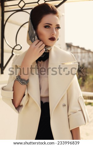 fashion outdoor photo of beautiful elegant lady wearing luxurious beige coat and silk scarf on her head