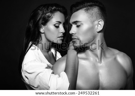 black and white fashion photo of sexy impassioned couple posing in dark studio