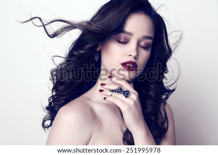 fashion studio portrait of gorgeous woman with dark hair and bright makeup with manicured nails and bijou
