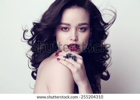 fashion studio portrait of gorgeous woman with dark hair and bright makeup with manicured nails and bijou
