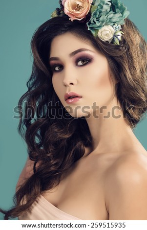 fashion studio portrait of beautiful sexy woman with dark hair and bright makeup with flower\'s headband