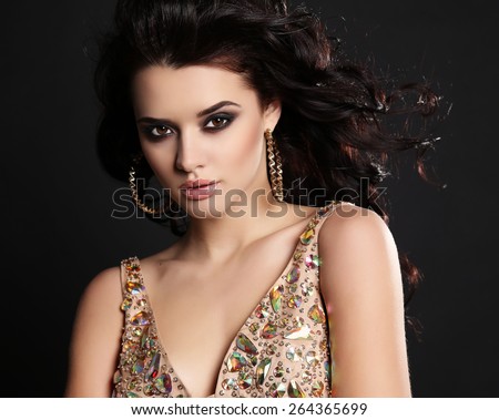 fashion studio photo of beautiful sensual woman with dark hair and bright makeup wearing luxurious sequin dress
