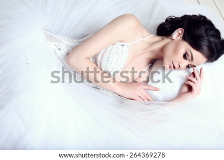 fashion studio photo of beautiful elegant bride with dark hair in luxurious wedding dress