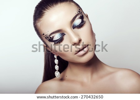 fashion studio portrait of beautiful young woman with dark  hair and bright extraordinary makeup