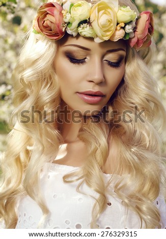 fashion outdoor photo of beautiful sensual woman with long blond hair and flower\'s headband posing in spring blossom garden