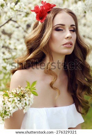 fashion outdoor photo of beautiful sensual woman with long red hair and flower\'s headband posing in spring blossom garden