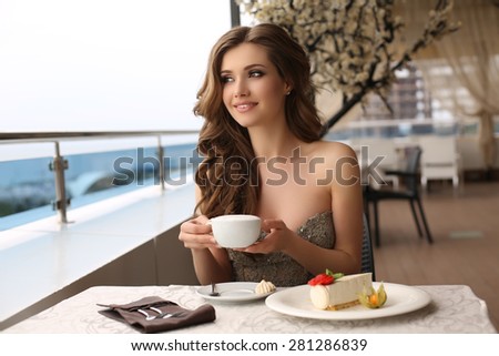 fashion outdoor photo of beautiful sensual woman with long dark hair in luxurious sequin dress posing in summer outdoor cafe,drinking a coffee
