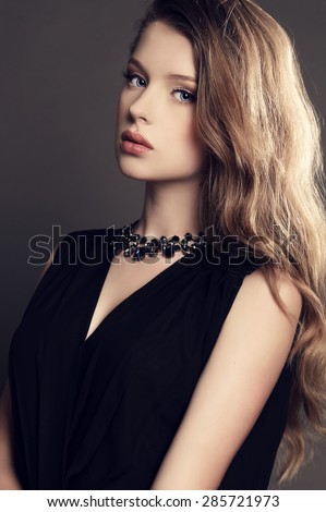 fashion studio photo of beautiful young girl with dark natural hair wearing black dress and bijou