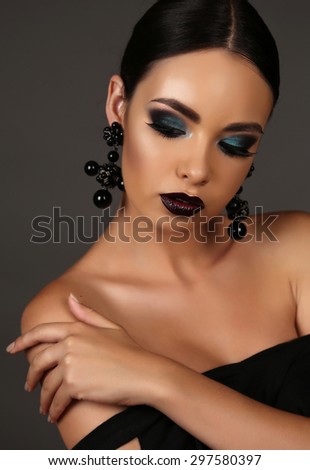 fashion studio portrait of beautiful girl with dark hair with bright extravagant makeup and bijou