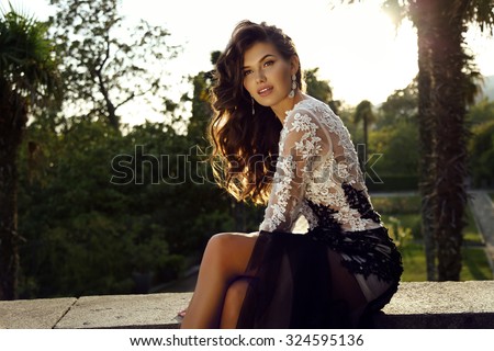 fashion outdoor photo of beautiful woman with dark hair wears luxurious dress,posing in summer park