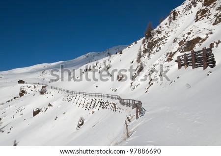 Winter landscape in austrian Alps with cabin and fencing
