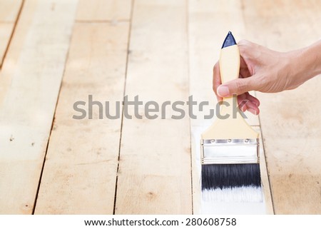hand worker holding brush painting white on wood texture