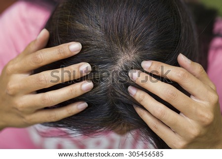 Young woman shows her gray hair roots