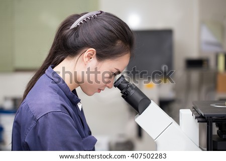 female scientist looking in microscope in laboratory Laboratory Microscope