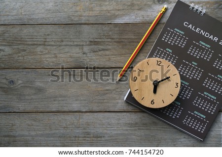 close up of clock, calendar and pencil on the table, planning for business meeting or travel planning concept