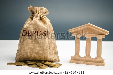 Bag of money with the word Deposit near the bank. The amount of money transferred by a person to a credit institution in order to receive income in the form of interest. Investment in bank