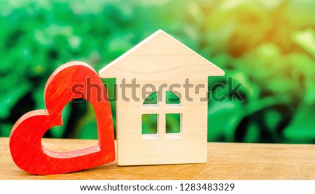 Wooden house and red heart. Concept of sweet home. Property insurance. Family comfort. Affordable housing for young families. Hotel for lovers on Valentine\'s Day.