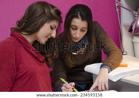Girls studying together at home, one girl helps out another one, selective focus on a girl in foreground