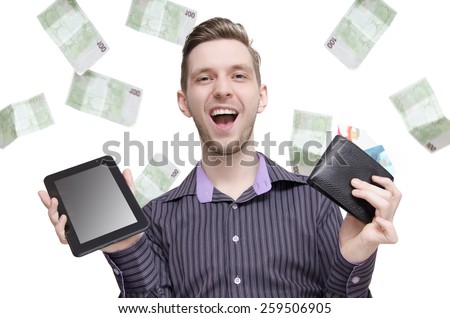 Happy young man making money on internet concept. Shopping online concept, smiling while holding tablet and wallet while money falls from sky, isolated white