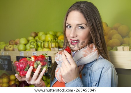 Young positive girl holding strawberries punnet and smiling