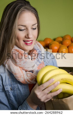 Beautiful natural brunette buying bananas and smiling