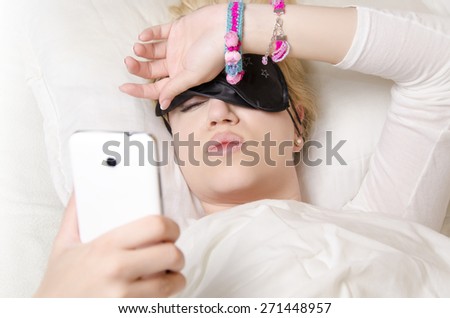 Pretty girl lying in bed pulling up sleeping mask to see what time is it/ wake up, or cant sleep concept