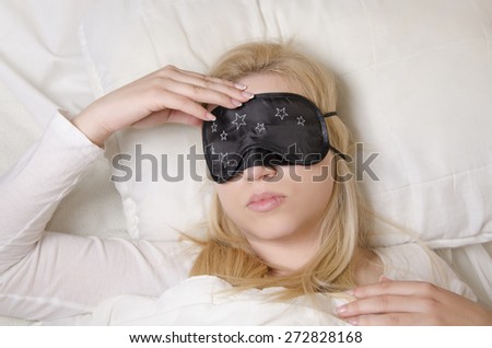 Blonde young girl with sleeping mask with headache, cant go to sleep