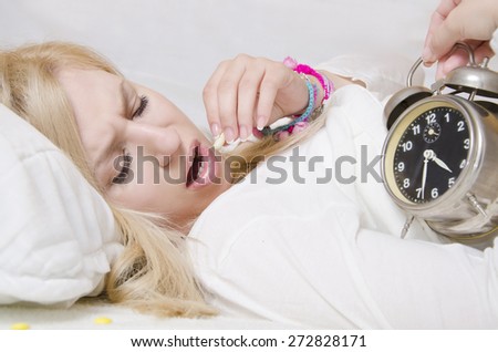 Insomnia young girl looking at clock and taking the sleeping pill
