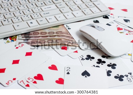 Cards over computer keyboard and smartphone. Concept of online card games.