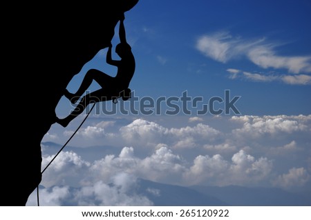 Climber silhouette high above clouds and mountains.