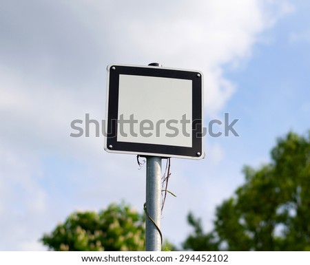 White metal sign with black frame bolted to a metal pole on the road