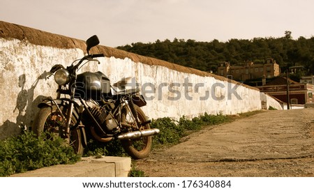 An Old Motor Cycle Parked Against A Fench